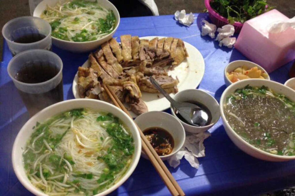 Bát miến ngan nóng hổi đầy thịt ngan, miến trắng, măng và hành trên bàn xanh vỉa hè Bãi Cháy.