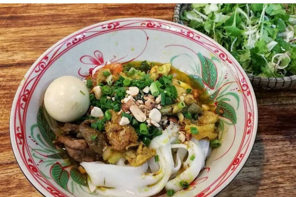 Tô mỳ Quảng tôm thịt đậm đà ăn kèm rau sống và bánh tráng nướng tại Mỳ Quảng Bà Mua.