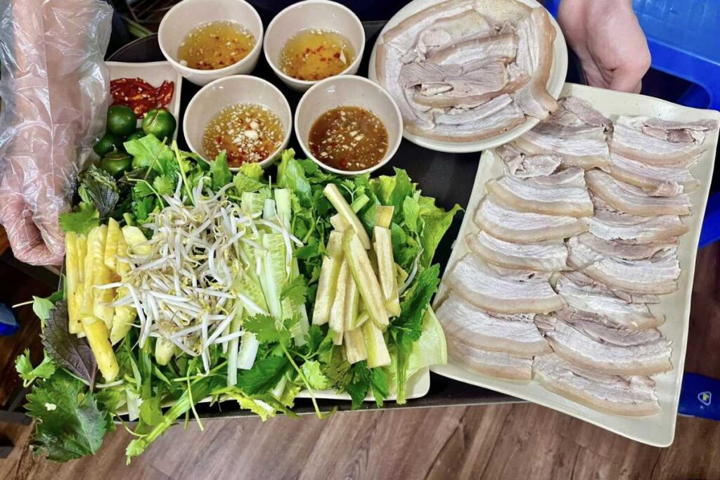 Mẹt bánh tráng cuốn thịt heo quay gồm thịt heo quay, bánh tráng, rau sống, mắm nêm và bát chấm.