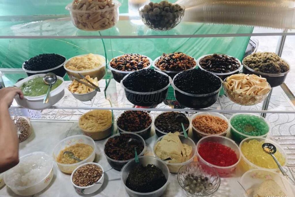 Tủ kính trưng bày đa dạng các loại thạch, hạt sen và nguyên liệu chè thanh mát tại Chè Nhà Cổ.