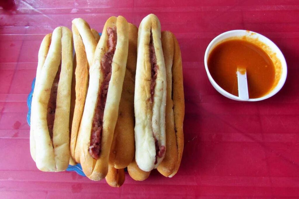 Thực khách thưởng thức bánh mì que cay nồng bên vỉa hè phố Đinh Tiên Hoàng trung tâm Hải Phòng.