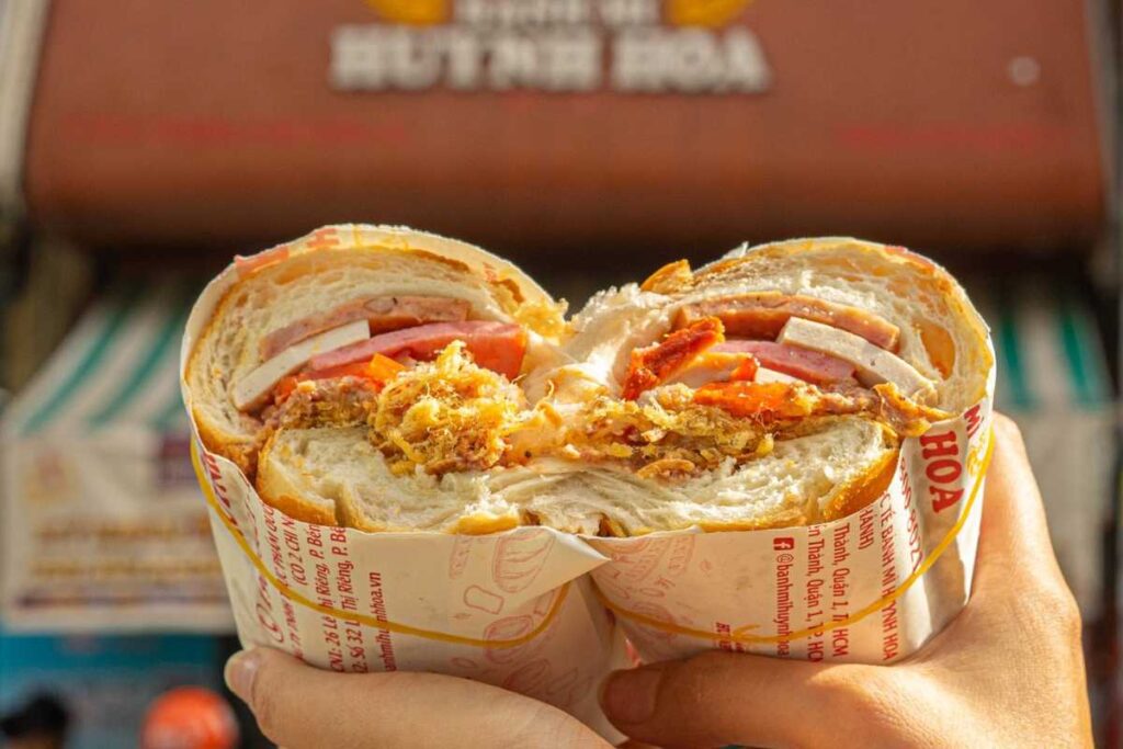 Ổ bánh mì Huỳnh Hoa cắt đôi lộ rõ lớp pate, thịt nguội và bơ đặc sánh cực kỳ hấp dẫn.