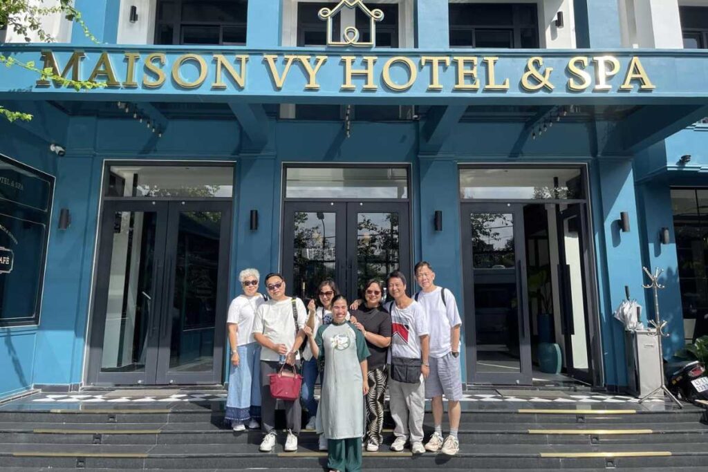 Ảnh nhóm sáu người check-in trước mặt tiền Maison Vy Hotel & Spa.