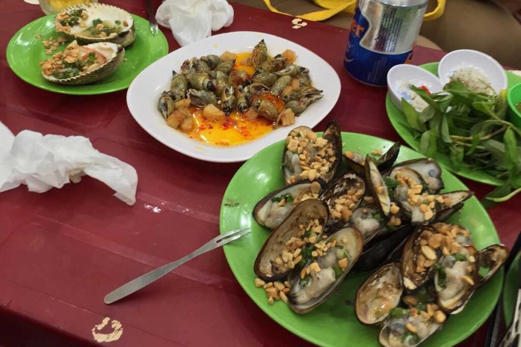 Các món ốc hương rang muối và ốc mỡ xào me nóng hổi trên bàn ăn tại quán Ốc Đào quận 1.